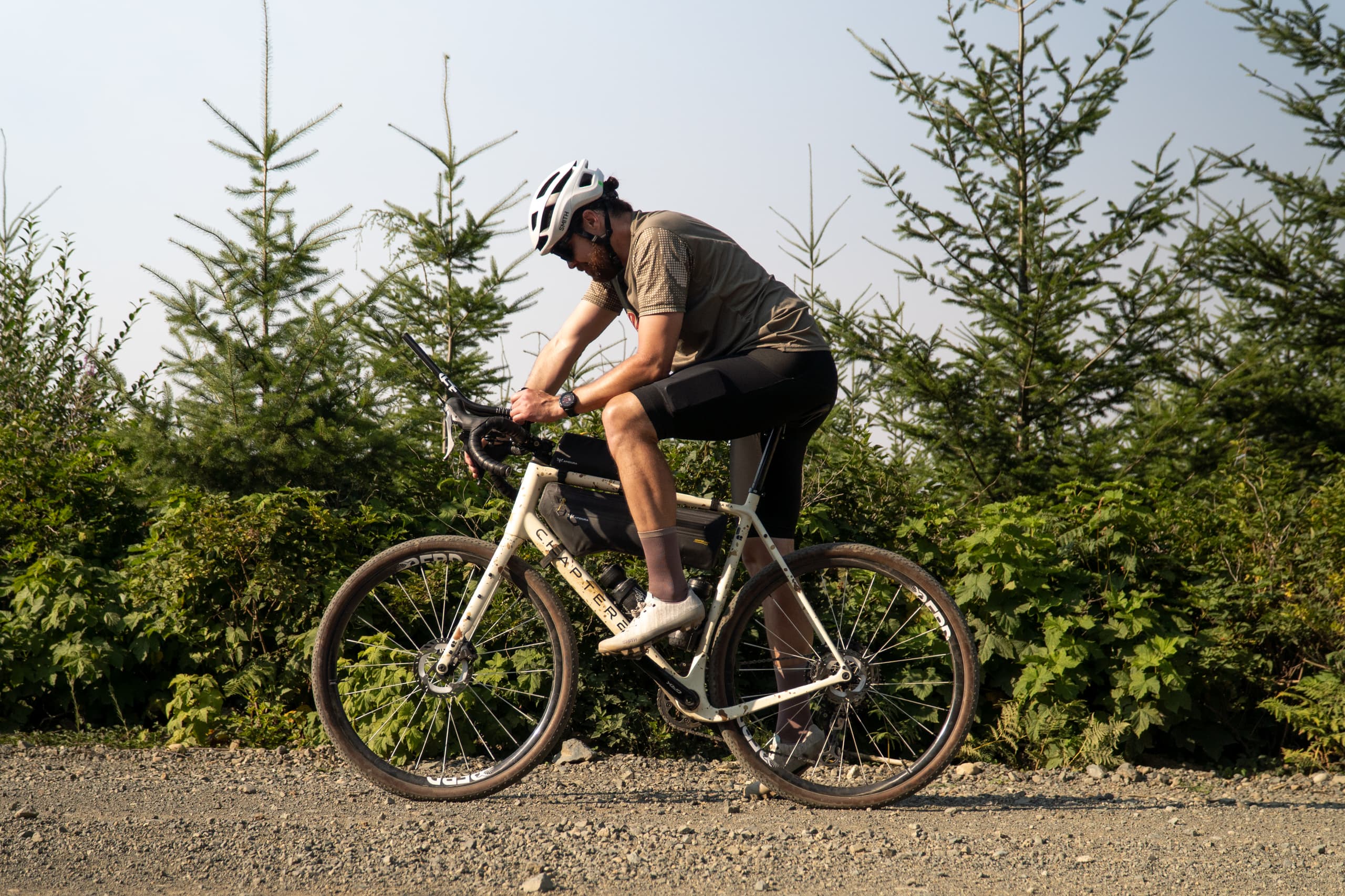 Riding upright through young pines on gravel.