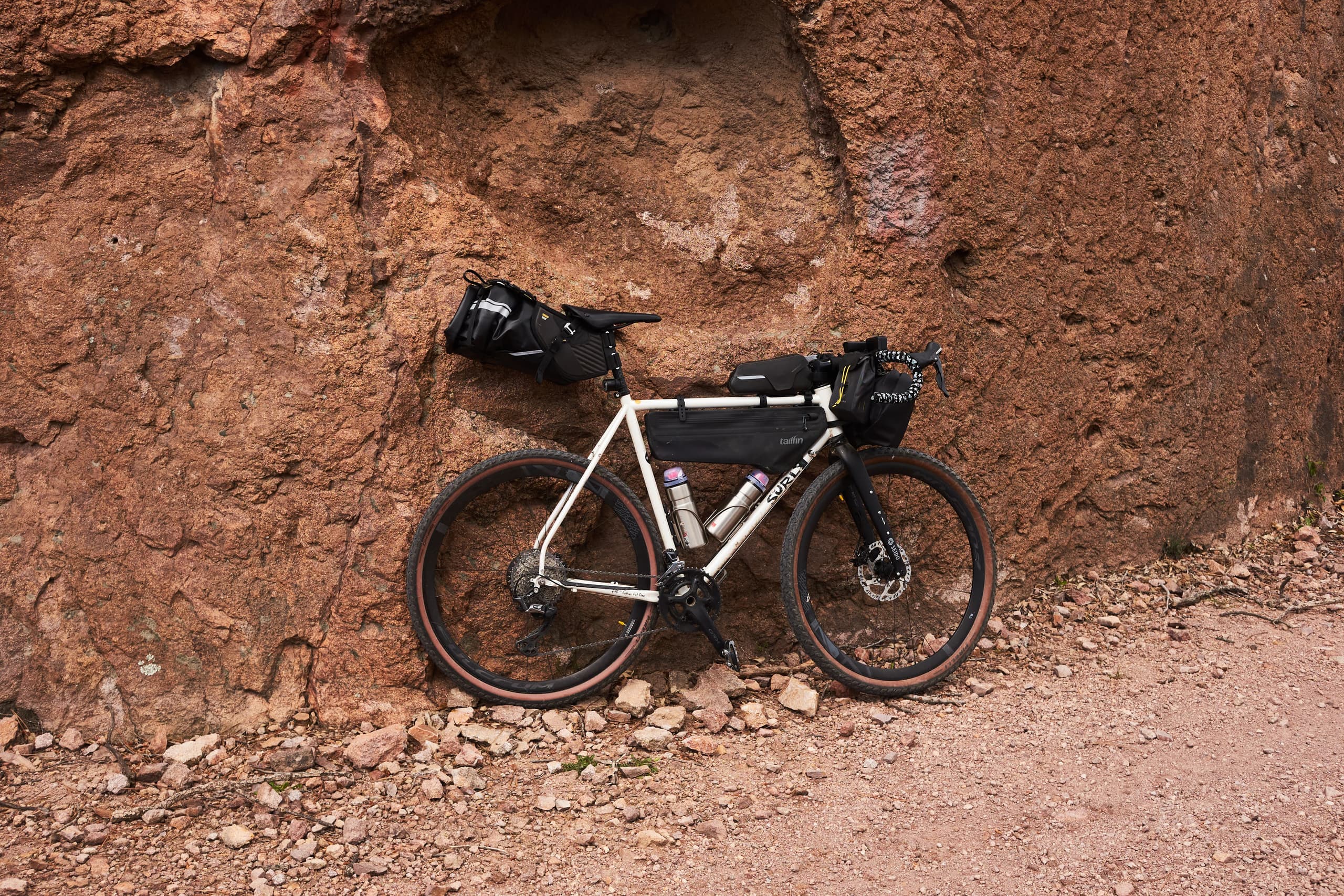 A loaded gravel bike against a red volcanic rock wall