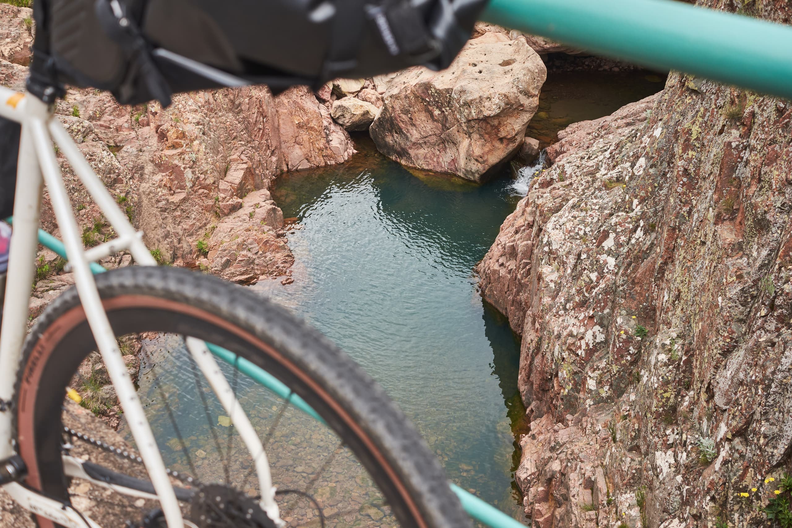 A bike detail beside a small red-rock pool