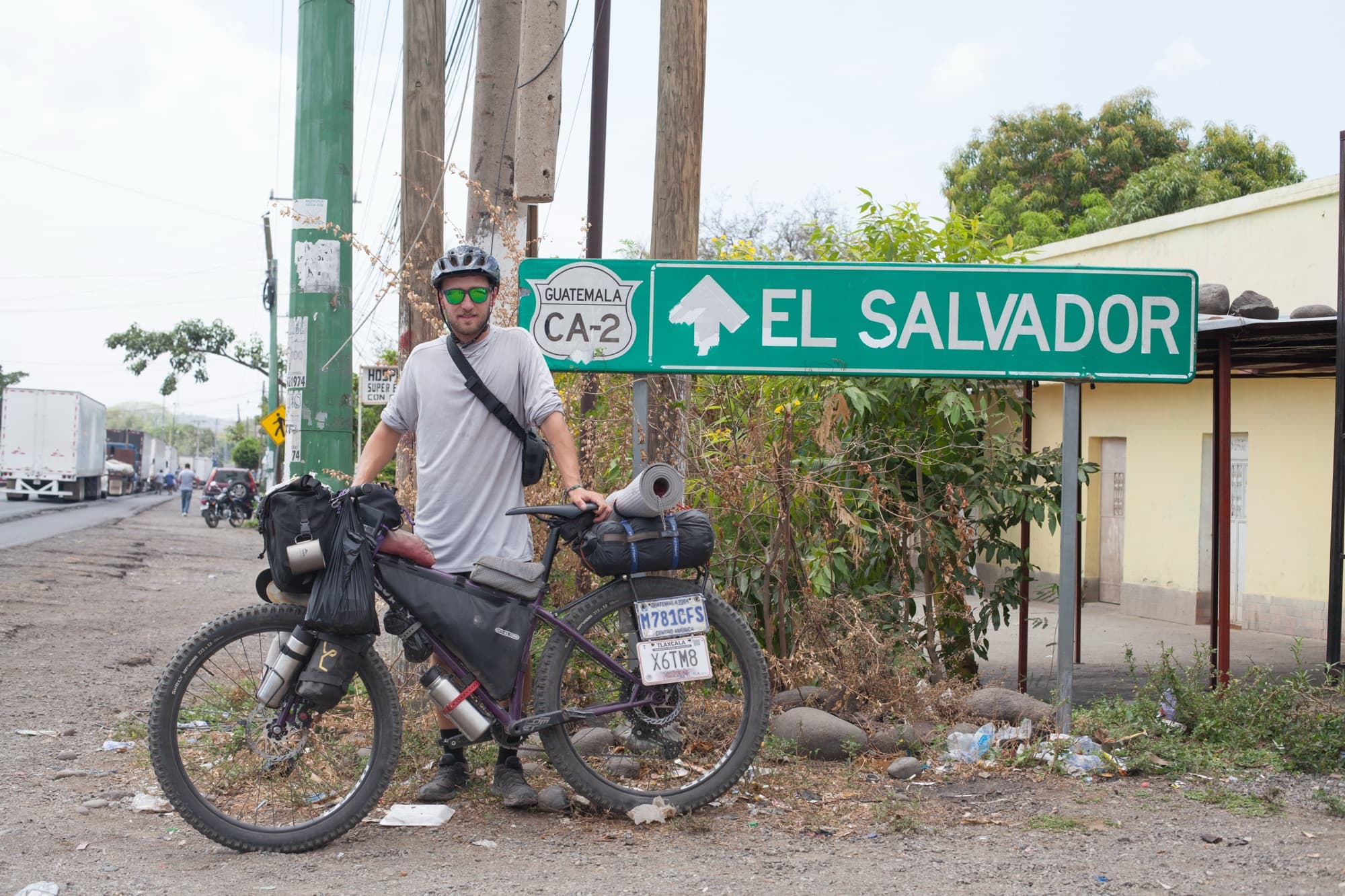 Posing with the loaded bike at the El Salvador border sign