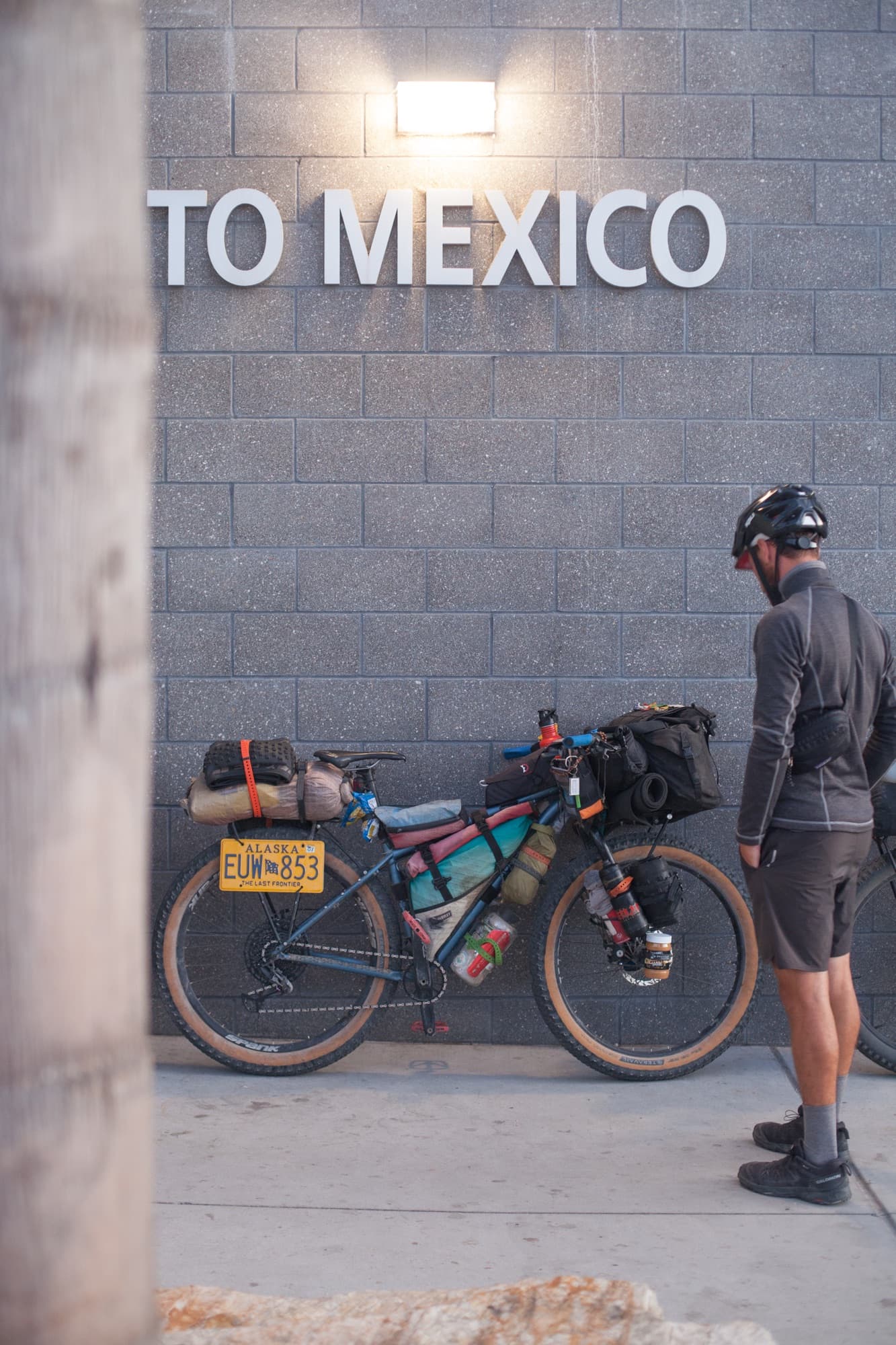A loaded bike leaning under a To Mexico sign at the border