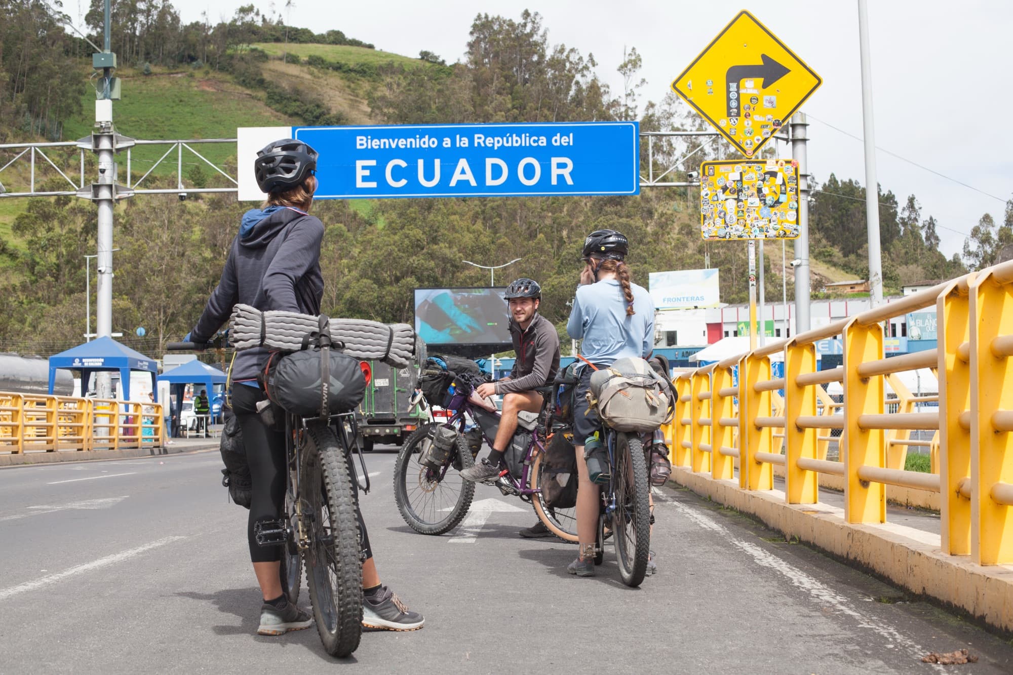 Riders pausing at the welcome sign on the Ecuador border bridge