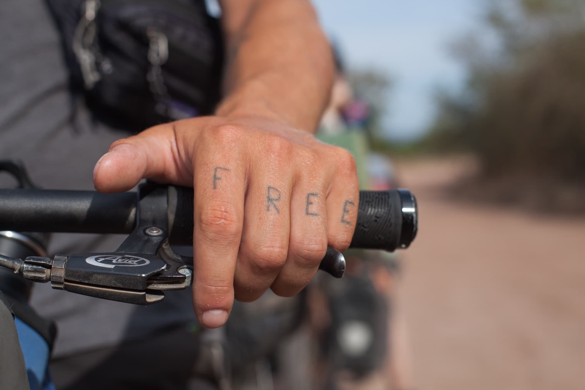 The word FREE written across four knuckles gripping the handlebars