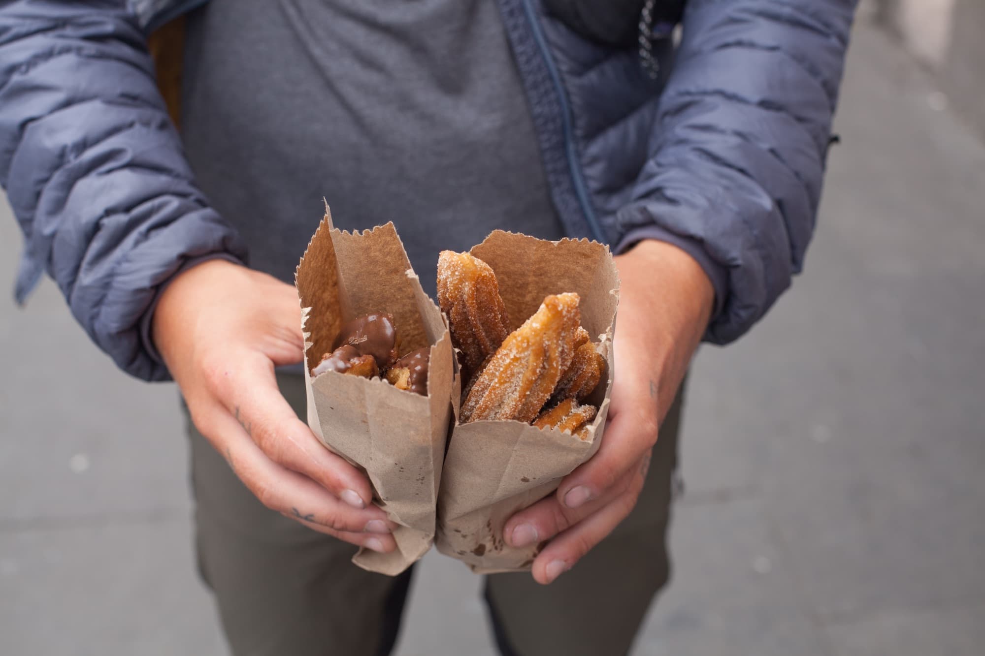 Two paper bags of pastries, held out to share
