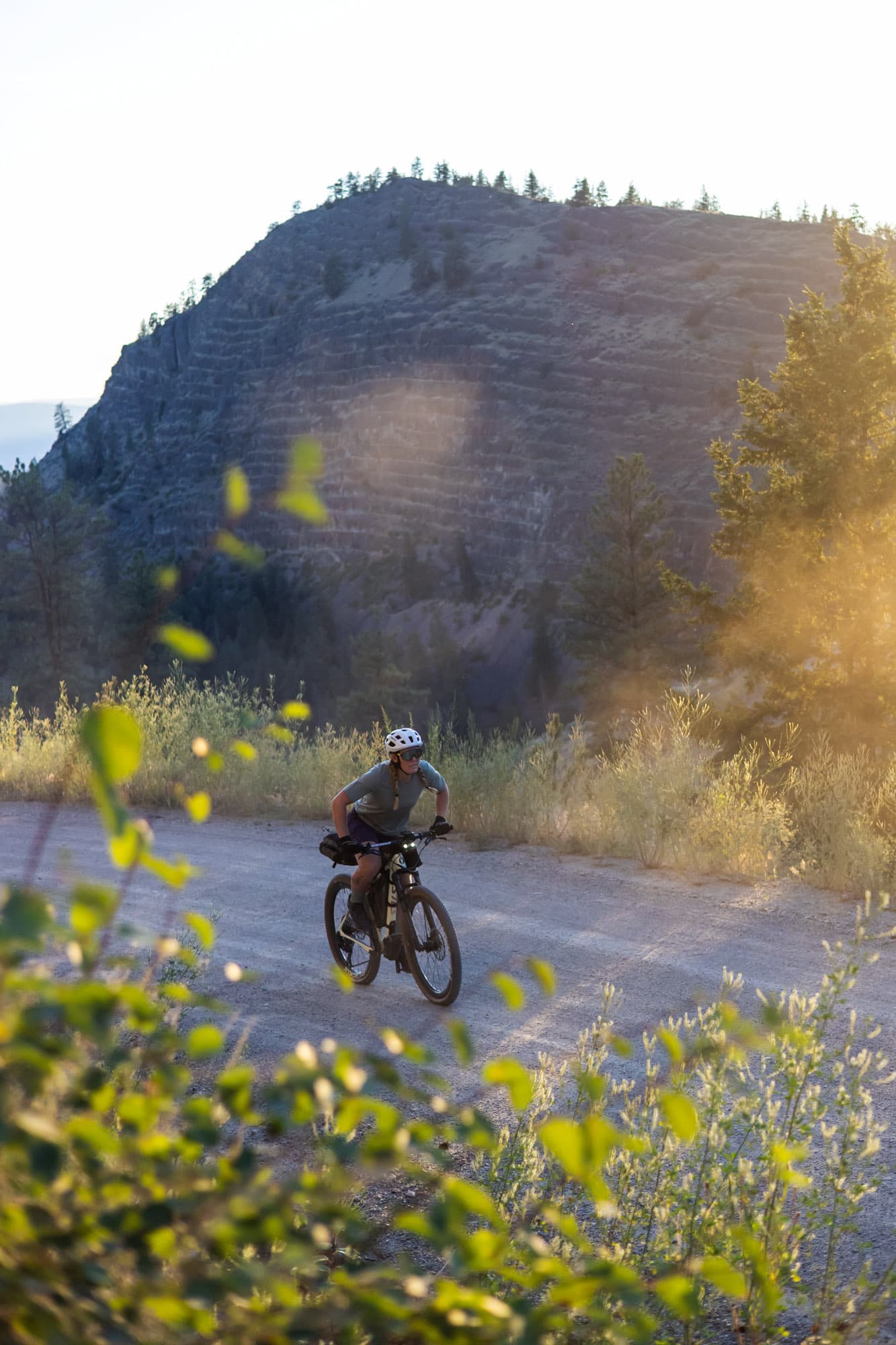 A rider on a gravel road below a rocky bluff.