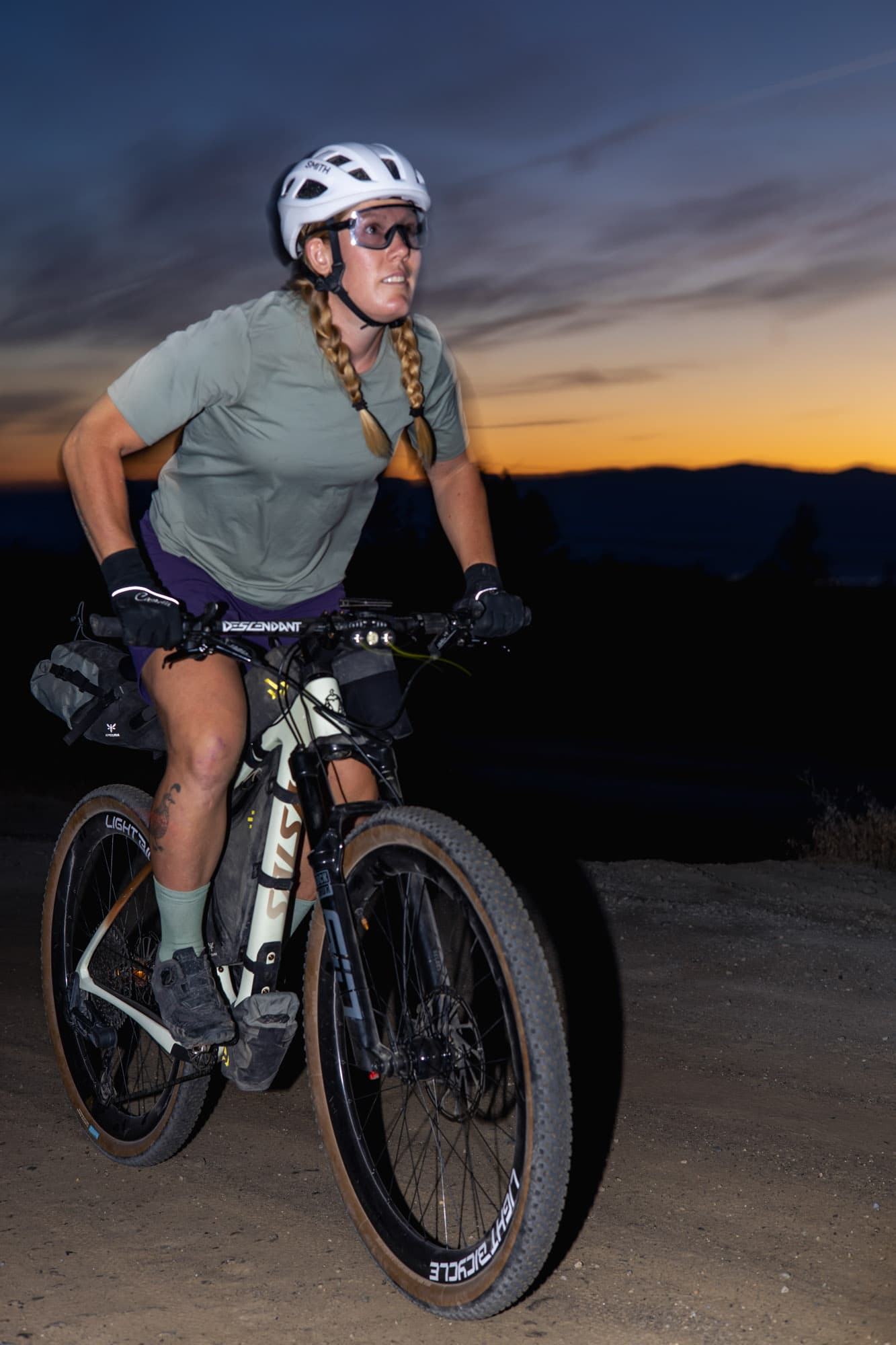 Meaghan over her bike against a dusk sky.