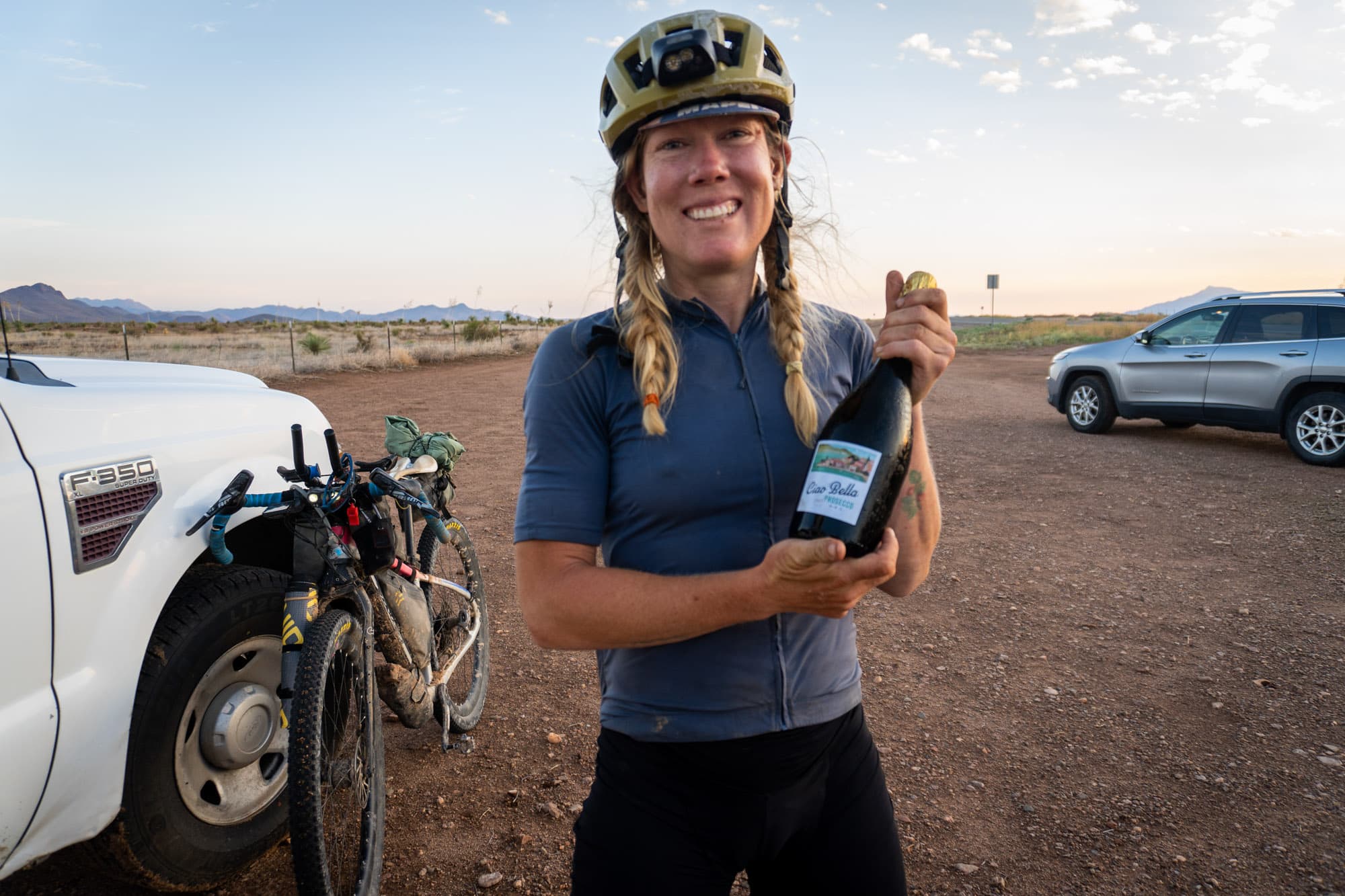 Meaghan celebrates with a bottle beside a truck in the desert.