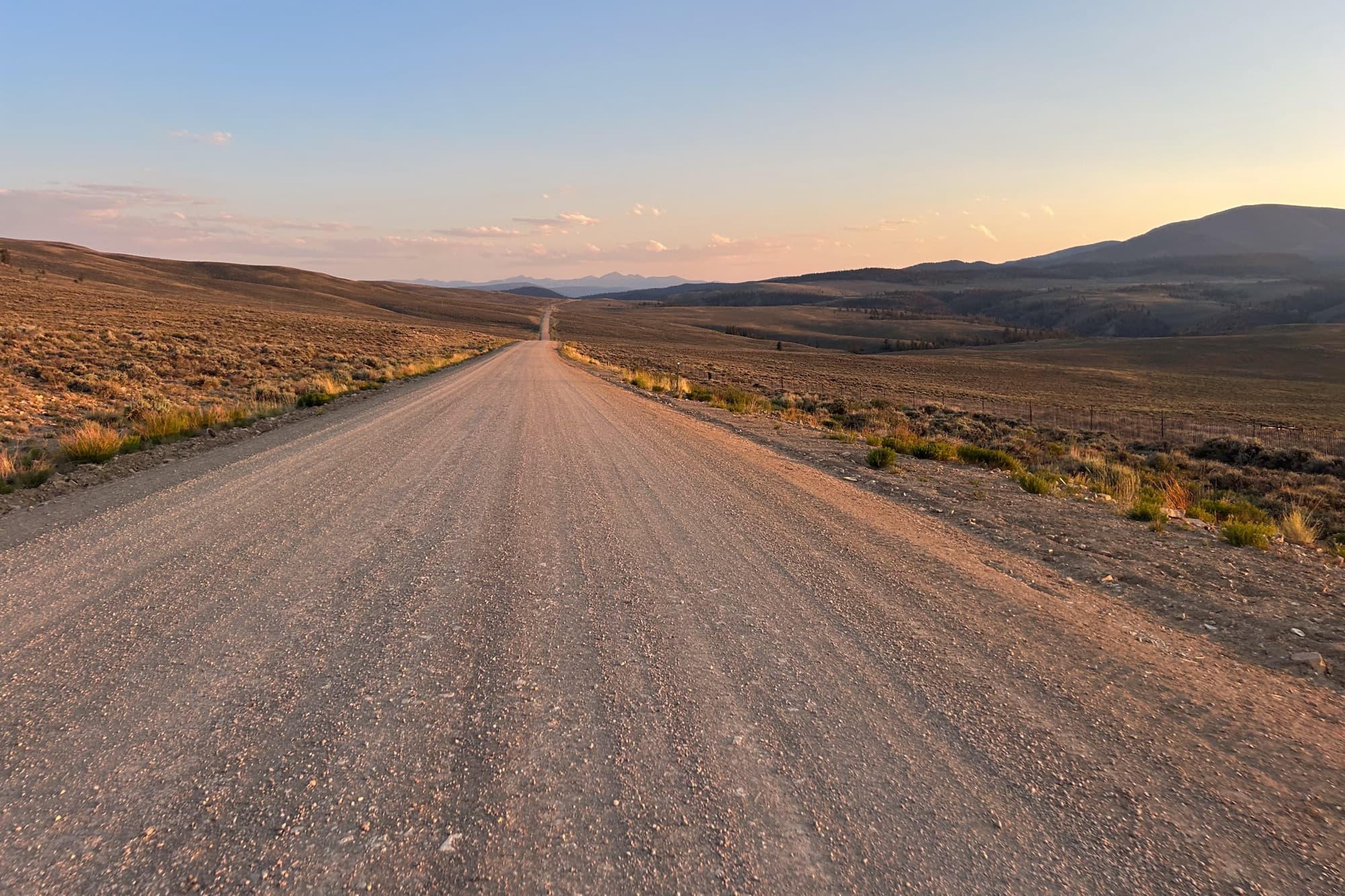 Dusk falls over an empty gravel road through the high desert