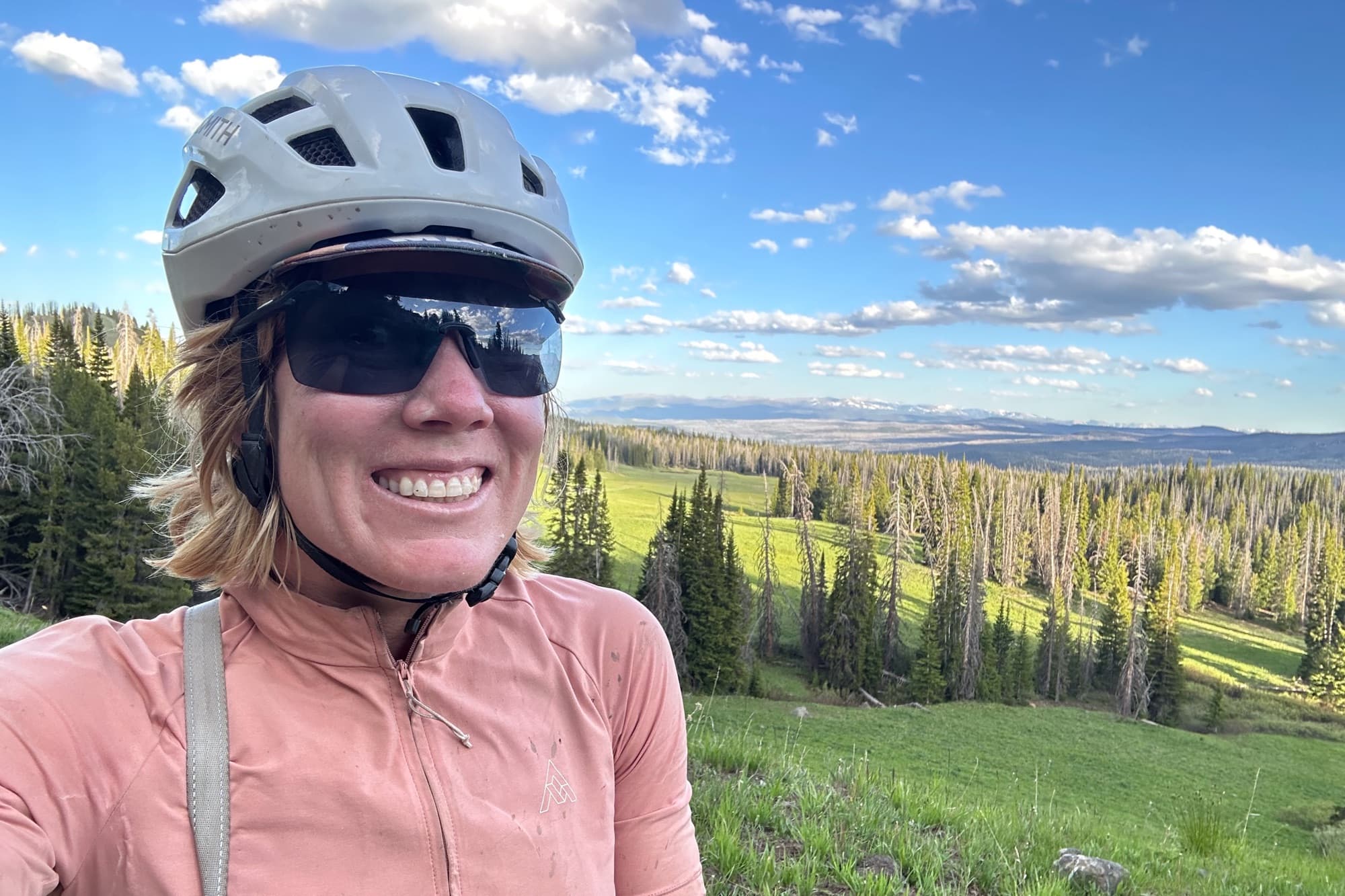 Meaghan grins high above a valley of meadows and timber
