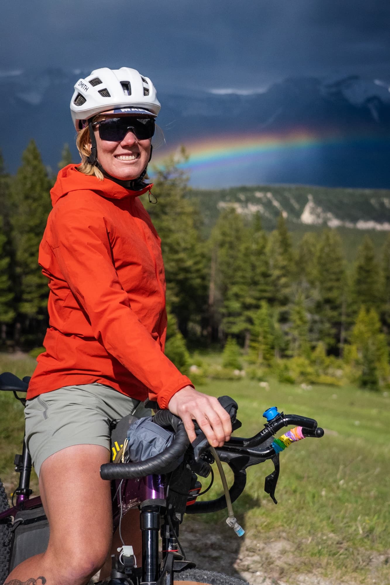Meaghan smiles from the saddle beneath a rainbow in the Canadian Rockies