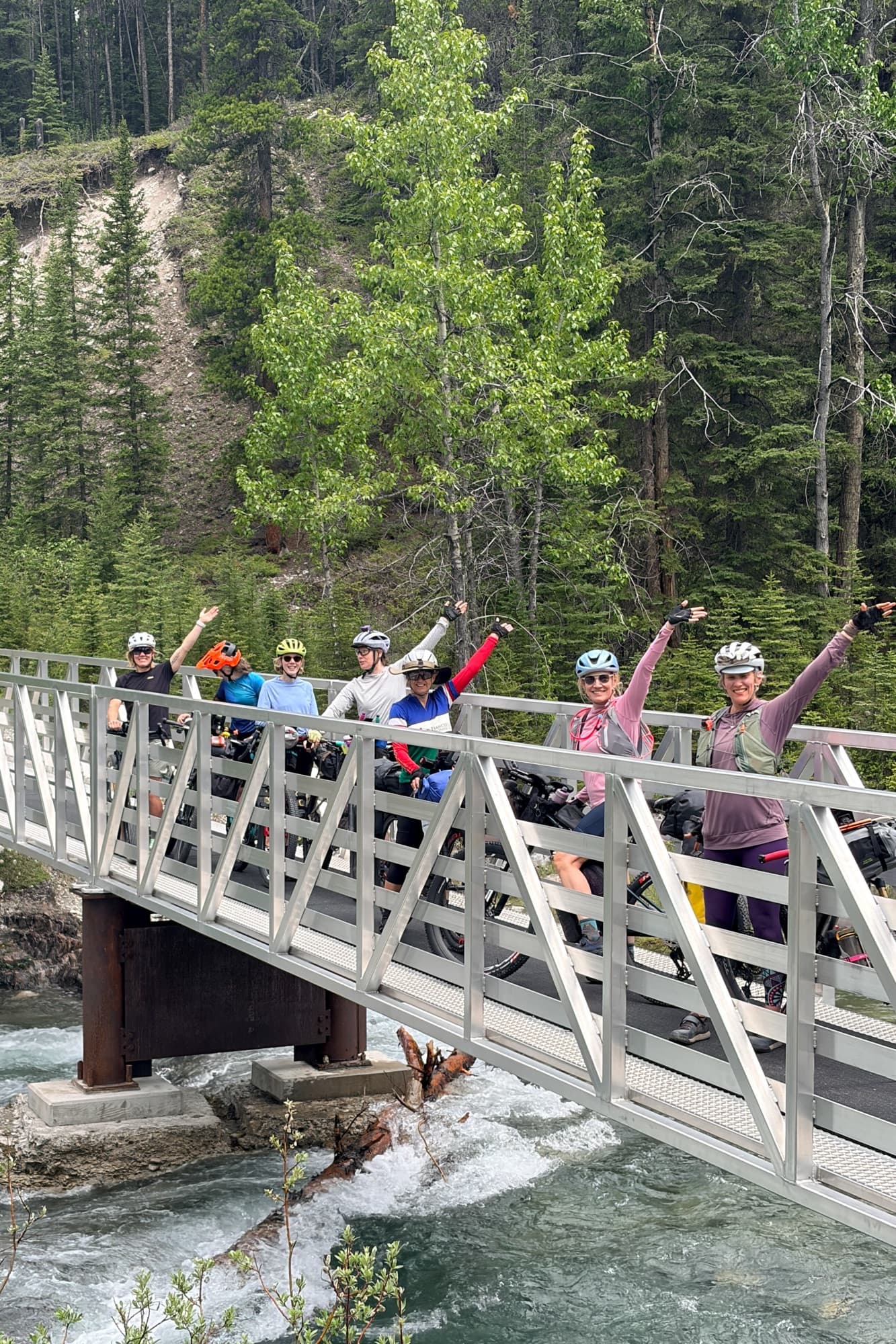 Riders raise their arms on a bridge during the Divide Collective meetup ride