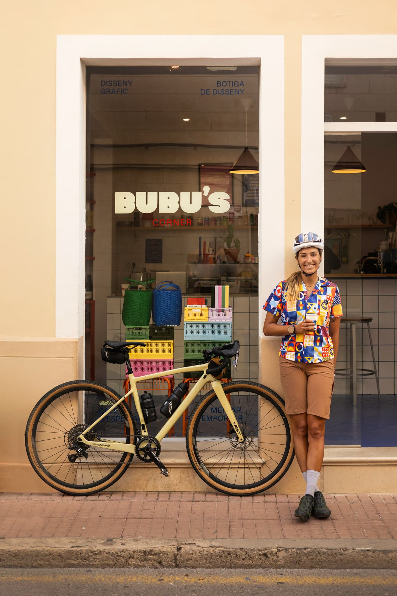 A Pamera rider poses with her gravel bike in front of BUBU's Corner shop in a Catalan town.