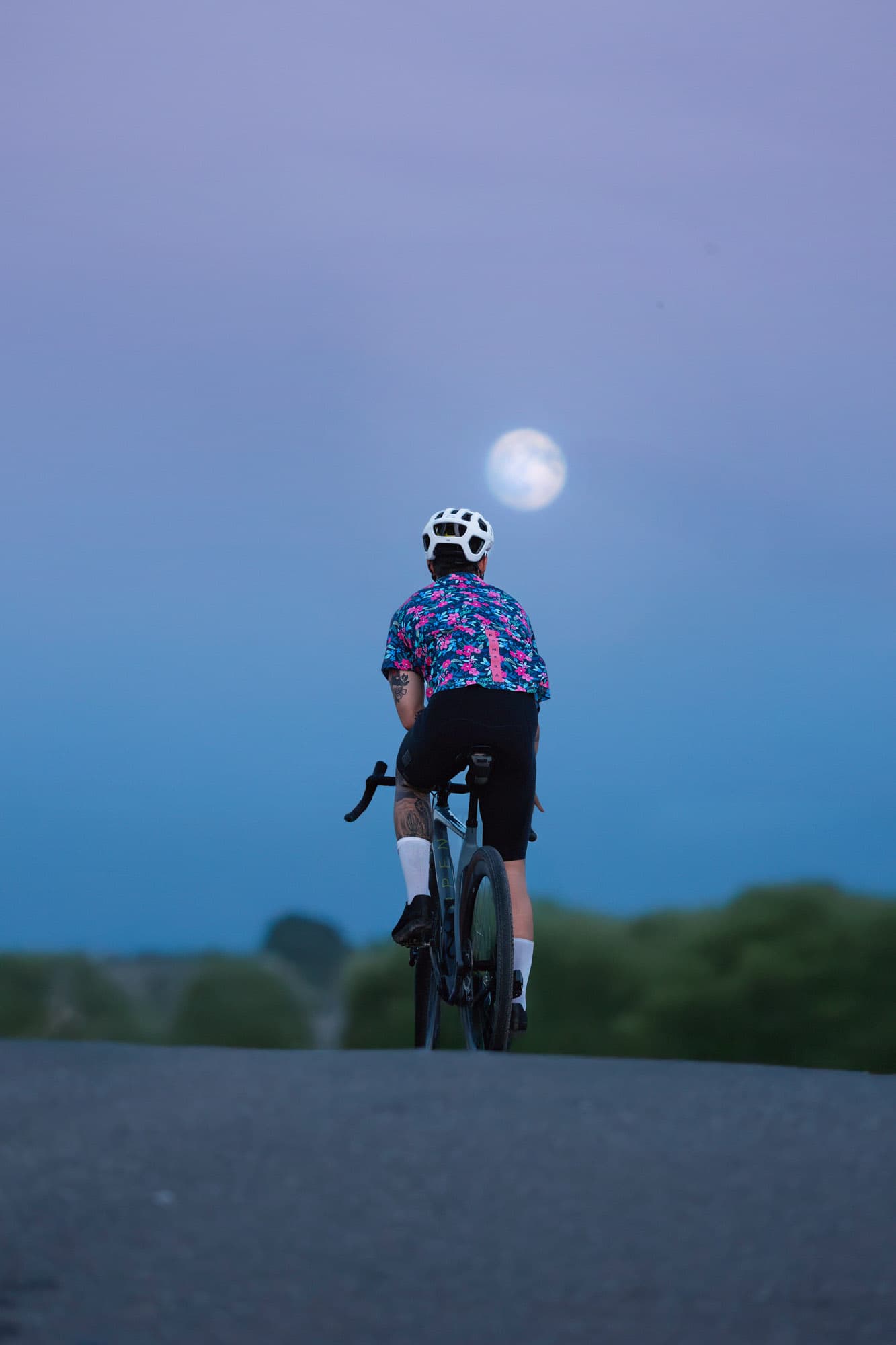 A solo Pamera rider silhouetted against a rising full moon at dusk.