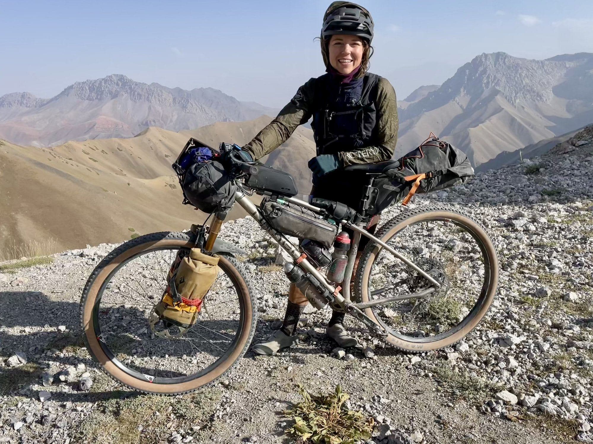 Britt standing with her bike on the rocky summit of Koy Djul Pass.